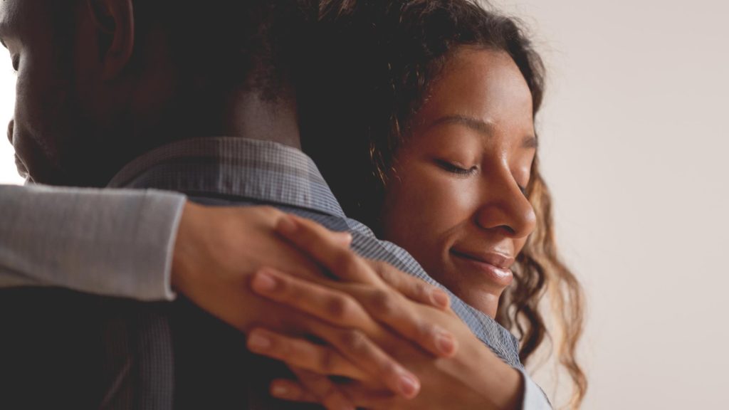 African-American female hugging an African-American male while smiling