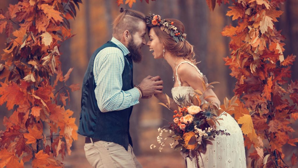 Photo of a bride and groom laughing to each other during a wedding in the fall season