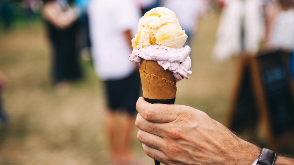 Hand holding an ice cream cone in a social gathering