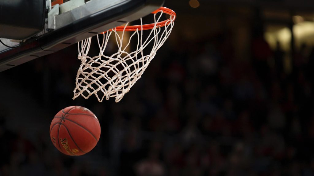 A basketball falling through the hoop in a basketball arena