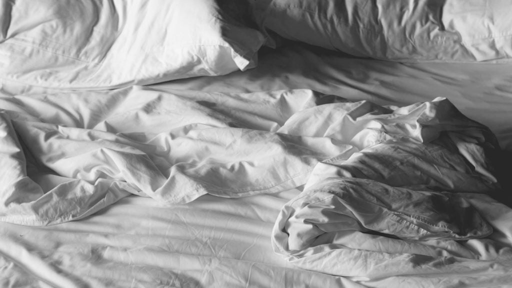 A ruffled pile of sheets and pillows indicating a restless night