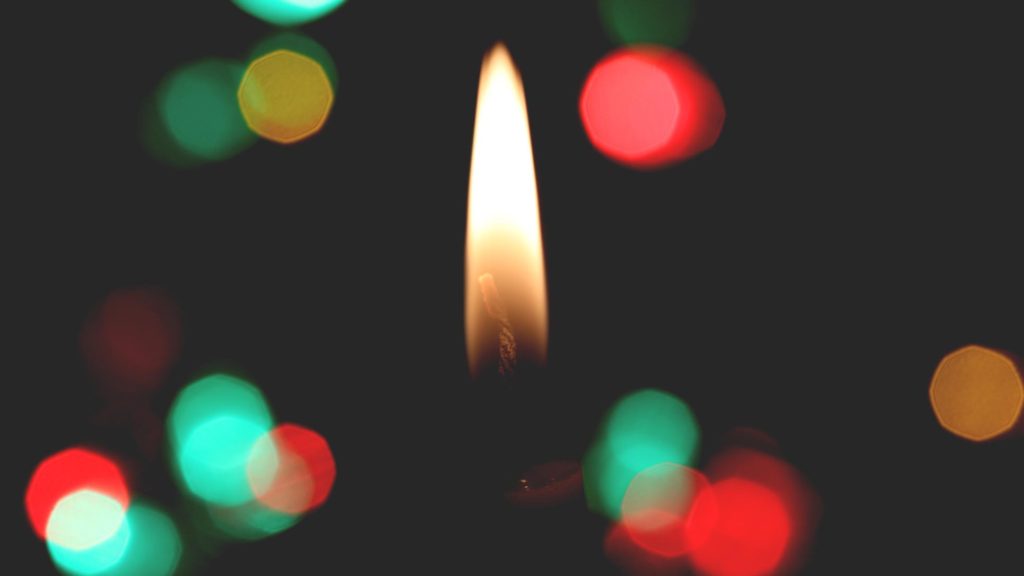 A candle flame isolated amongst out of focus holiday lights